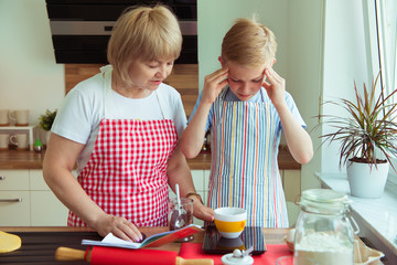 Happy grandmother with her grandchild having fun during baking muffins