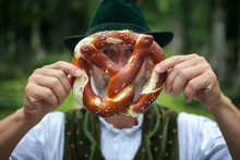Bavarian Man Holding A Pretzel In Front Of His Face