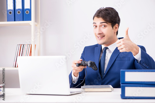 Fotomural Young handsome businessman playing computer games at work office
