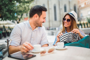 Wall Mural - Beautiful loving couple sitting in a cafe enjoying in coffee and conversation after shopping