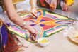 Bride's friend helps coloring the traditional rice art (Rangoli) on the floor for indian wedding