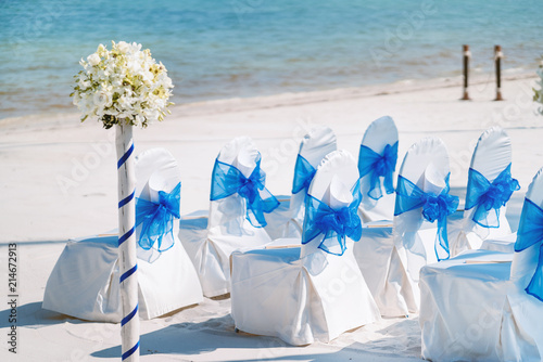 Fotografia, Obraz A group of white spandex chairs cover with blue organza sash for beach wedding v