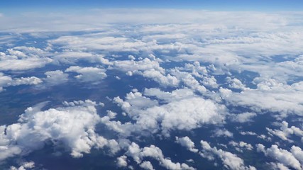 Wall Mural - flying over picturesque white clouds on the deep blue sky. beautiful moving clouds view from airplan