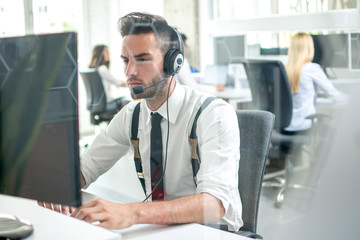 Handsome customer support help operator working on computer in call centre