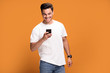 © neonshot - Smiling handsome man with mobile phone on yellow background.