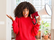 © Krakenimages.com - African american woman holding megaphone speaker very happy and excited, winner expression celebrating victory screaming with big smile and raised hands