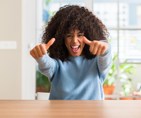 Sticker - African american woman at home approving doing positive gesture with hand, thumbs up smiling and happy for success. Looking at the camera, winner gesture.