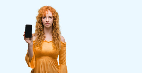 Sticker - Young redhead woman showing smartphone with a confident expression on smart face thinking serious