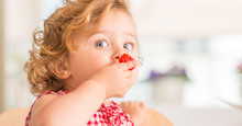 Beautiful Blonde Child With Blue Eyes Eating Strawberry At Home.