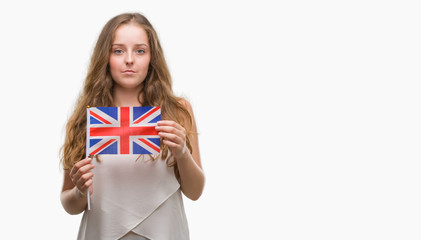 Sticker - Young blonde woman holding flag of UK with a confident expression on smart face thinking serious