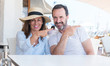 © Krakenimages.com - Middle age couple sitting at terrace very happy pointing with hand and finger to the side