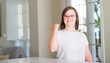 © Krakenimages.com - Down syndrome woman at home pointing and showing with thumb up to the side with happy face smiling
