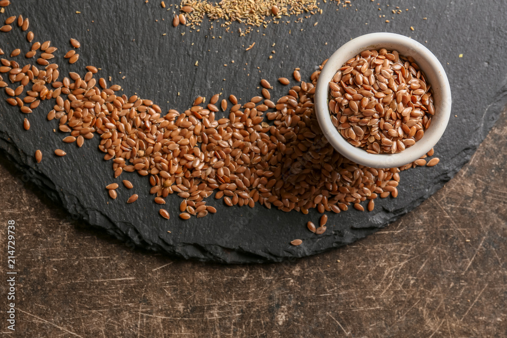 Slate plate with flax seeds on grey background
