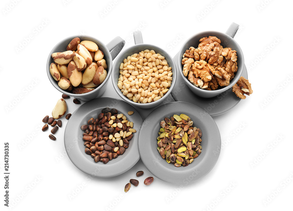 Cups and plates with different nuts on white background