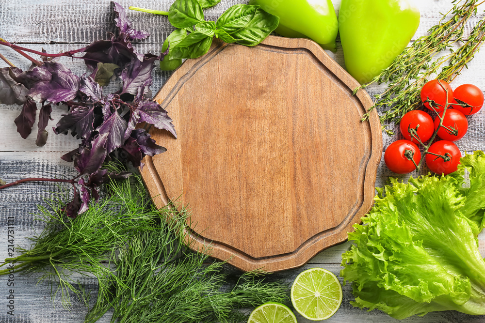 Composition with fresh herbs, vegetables and board on wooden background