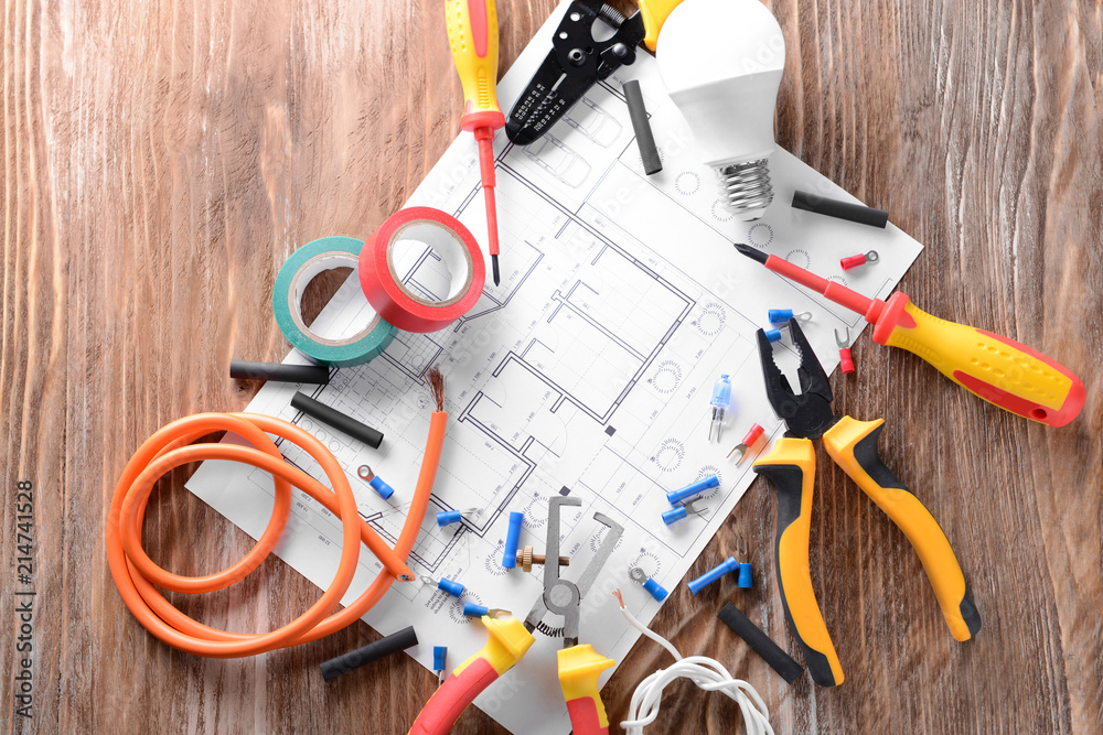 Electrician's supplies with house plan on wooden background