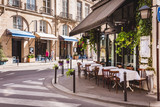 Fototapeta Uliczki - Cozy street with tables of cafe  in Paris, France