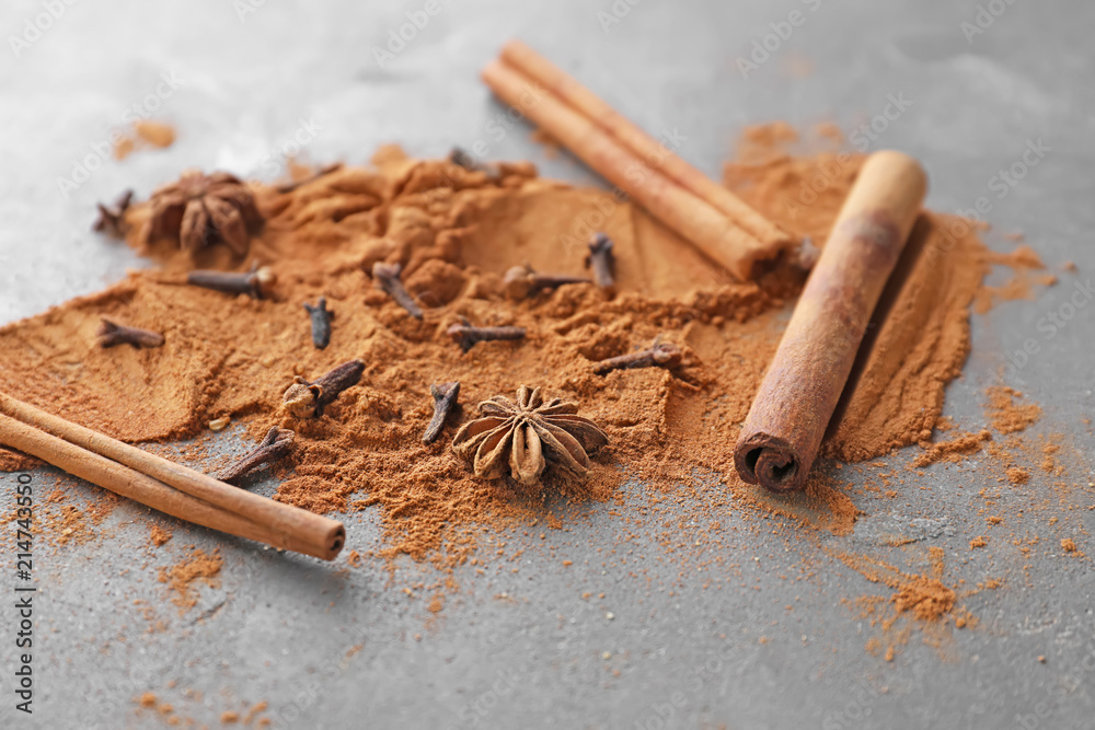 Aromatic cinnamon sticks, powder and spices on grey background