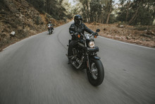 Man Riding A Black Classic American Motorcycle On The Road In The Mountains.