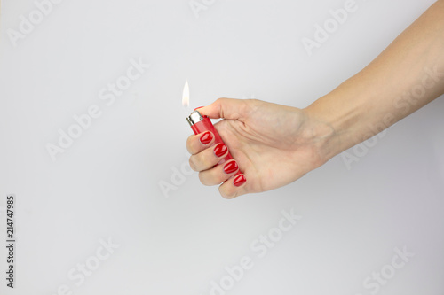 Fotografía red lighter with fire in woman's hand with red nails isolated on white backgroun