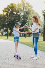 excited girl. smiling little girl feeling really excited standing on skateboard near her active cari