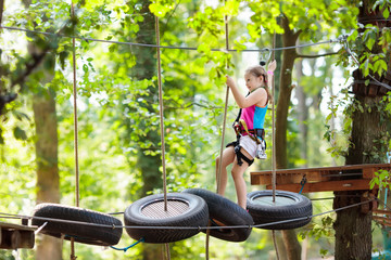 Child in adventure park. Kids climbing rope trail.