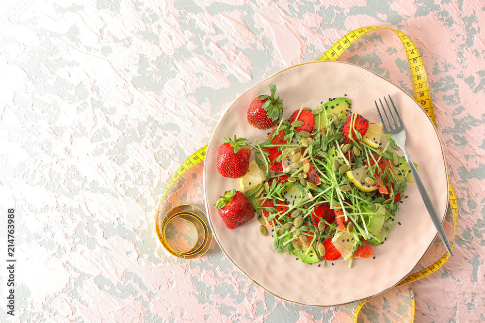 Plate with delicious fresh salad and measuring tape on table. Diet concept