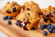 Freshly Baked Blueberry Muffins With An Oat Crumble Topping On A Natural Wooden Board