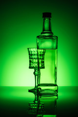 Wall Mural - bottle of absinthe with lead glass on mirror surface and dark green background