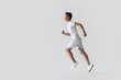 side view of young asian male athlete running on grey background