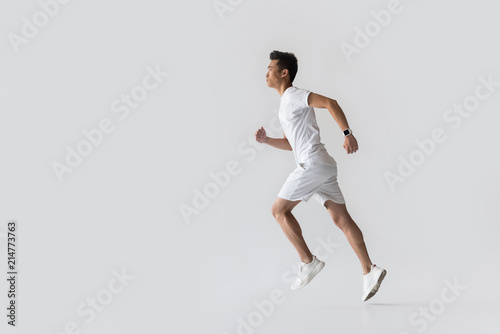 Fotografía side view of young asian male athlete running on grey background