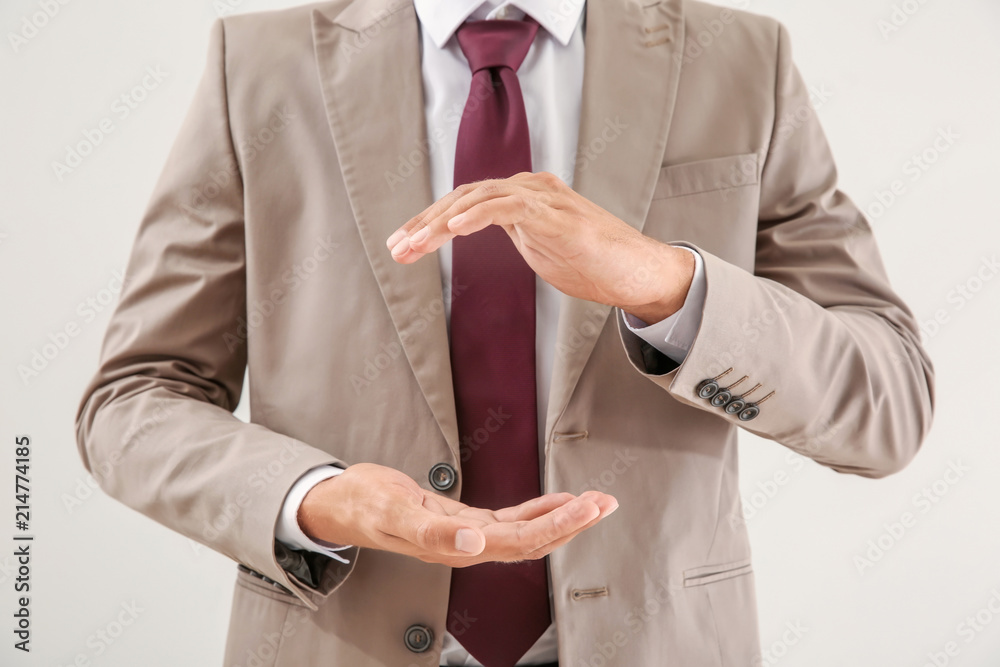 Businessman holding imaginary clock on light background. Time management concept