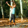 © Microgen - Woman Exercising With Elastic Band Outdoors in The Fall
