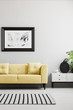 © Photographee.eu - Poster above yellow sofa in minimal grey living room interior with rug and cupboard. Real photo