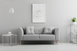 © Photographee.eu - Poster above grey couch in minimal living room interior with lamp above table. Real photo