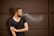 © aleksandr_yu - A young handsome white bearded man in black t-shirt smokes a cigarette in the street in the spring. Close up.