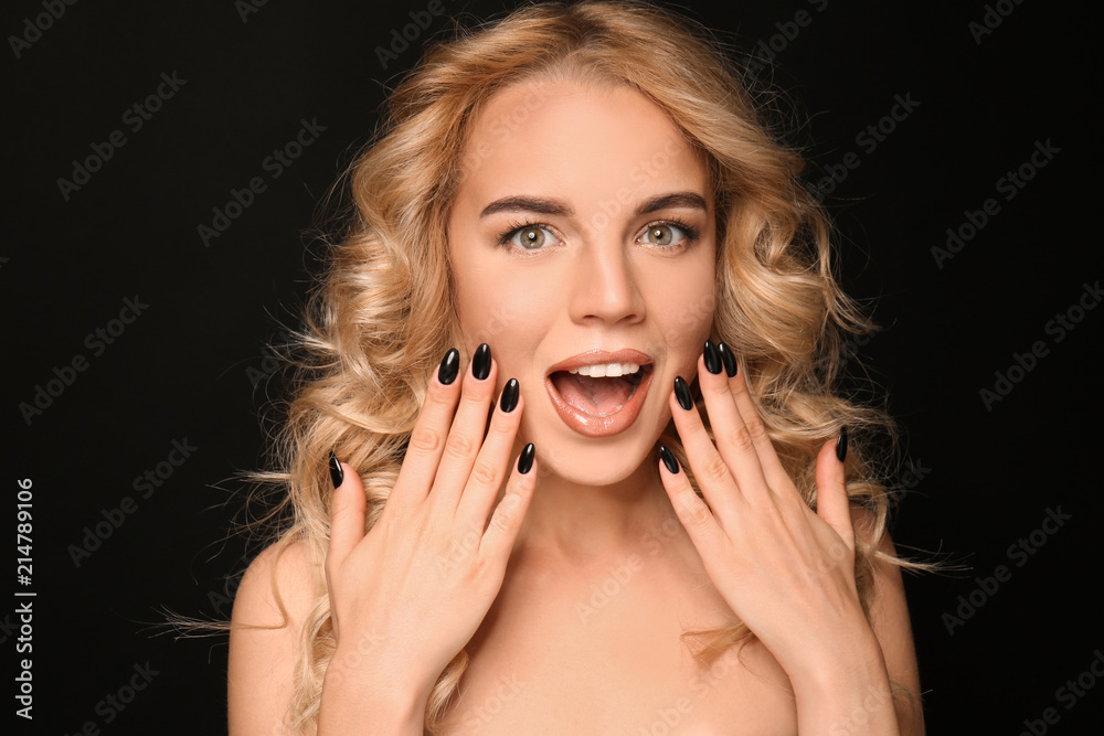 Beautiful young woman with professional manicure on black background
