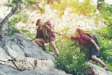 Group Hiker woman helping her friend climb up the last section of sunset in mountains. Traveler teamwork walking in outdoor lifestyle adventure and camping. Travel Concept.