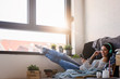 © lordn - Beautiful young woman at home enjoys listening music through headphones