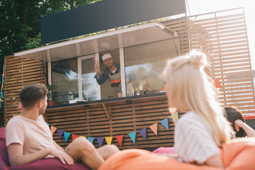 Poster - happy chef working in food truck and smiling to young customers outside