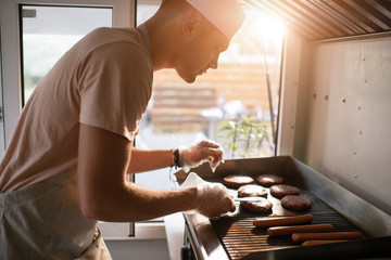 Wall Mural - side view of chef preparing meat for burgers in food truck