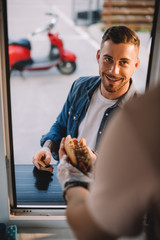 Canvas Print - cropped image of chef giving tasty hot dog to handsome customer in food truck