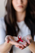 © lordn - Woman holding red ribbon on her palms. AIDS awareness symbol