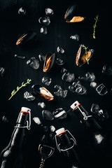 Wall Mural - flat lay with bottle opener, bottles of beer, mussels and ice cubes arranged on dark tabletop