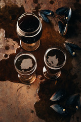 Wall Mural - top view of glasses of cold beer and mussels shells on rust surface