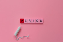 Menstruation Concept: Word Period Spelled With Pink Letters On Pink Background With A Tampon