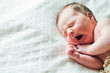 © kaloriya - Newborn baby sleeping and yawning on white sheets