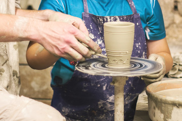 A raw clay pot in the hands of a potter. Workshop in the pottery workshop