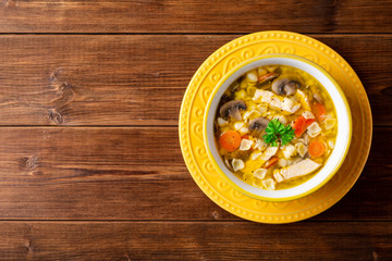 Wall Mural - Chicken soup with mushrooms, vegetables and pasta in bowl on wooden table.