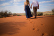 A pretty couple walks hand in hand on the red sand dunes in the kalahari region of south africa